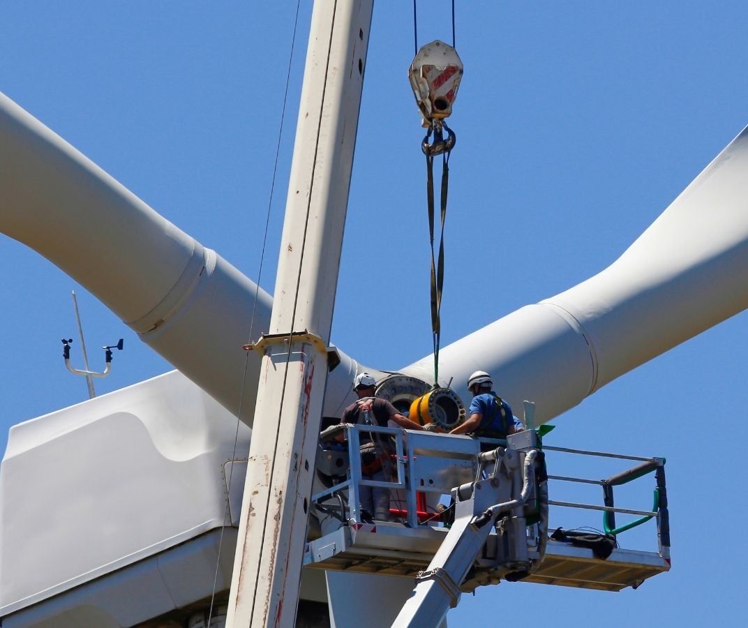 Techniciens effectuant des travaux de maintenance sur une éolienne.