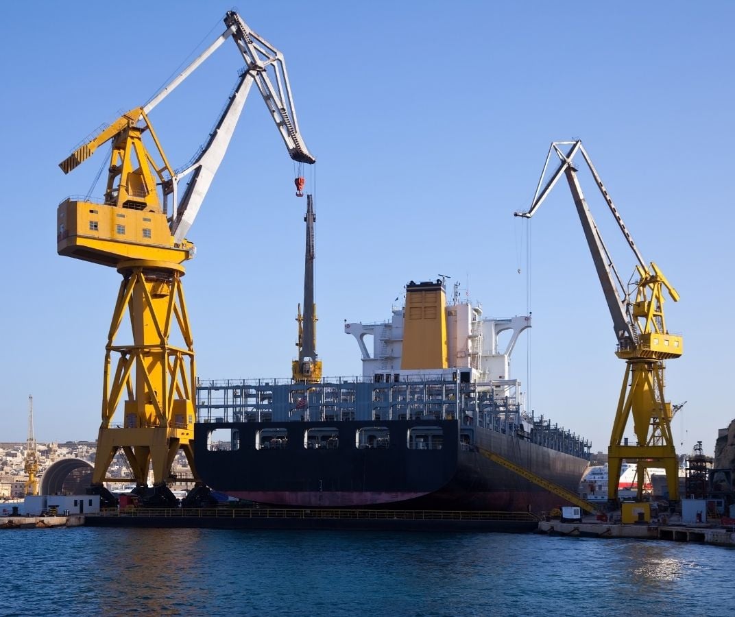 Navire marchand dans un chantier naval avec de grandes grues portuaires.